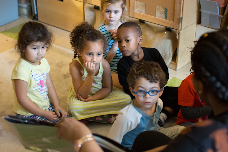 A group of children are seen listening to a story.