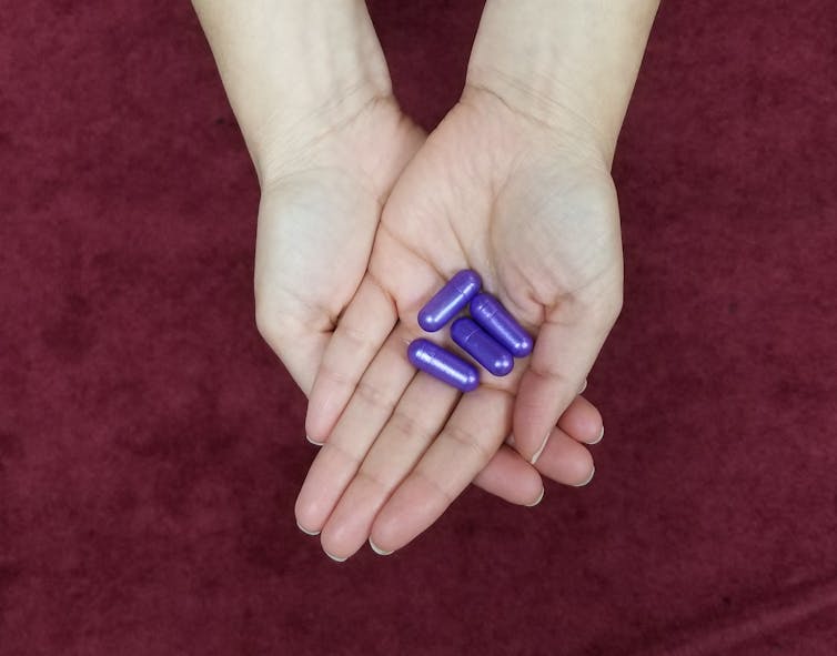 Large purple pills held in the palm of a hand