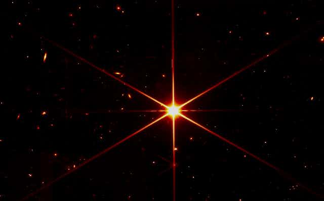 A photo from the James Webb Space Telescope of a bright orange star in sharp detail.