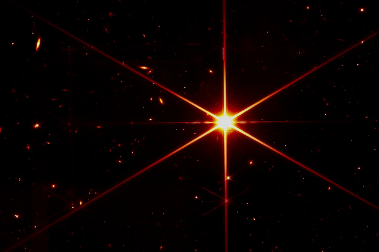 A photo from the James Webb Space Telescope of a bright orange star in sharp detail.
