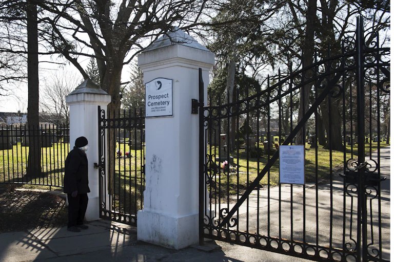A cemetery with closed gates, a woman looks on