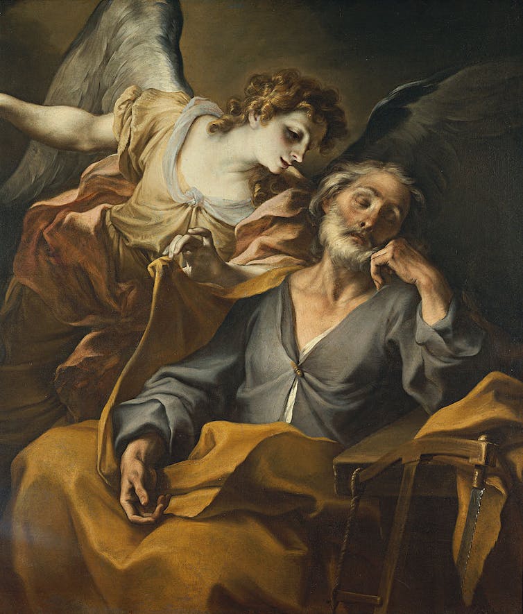 A painting shows an older man with a beard, with blue and yellow robes, being visited by a whispering angel while he sleeps.