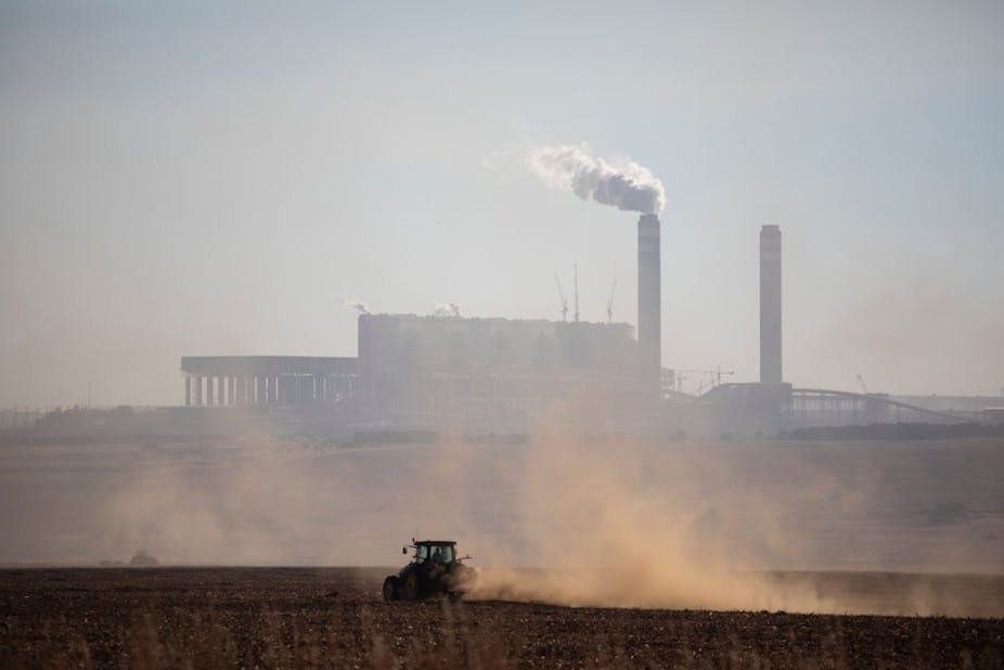 A tractor in front of a power station, dust and smoke in the image.
