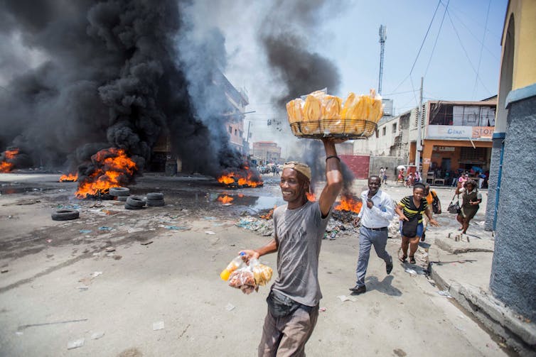 Man walks in street with burning tyres behind