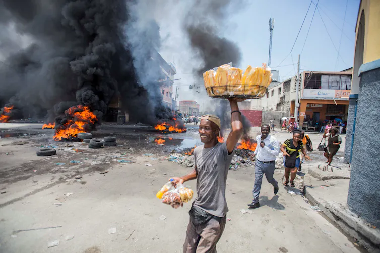 Man walks in street with burning tyres behind