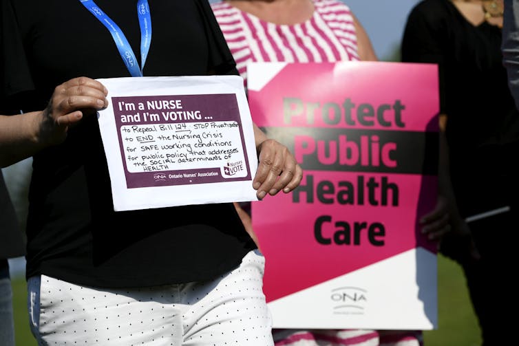 Pro-public health signs are held by nurses.