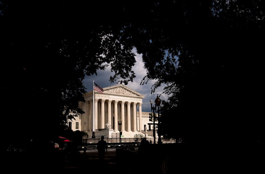 The Supreme Court building is framed by trees.