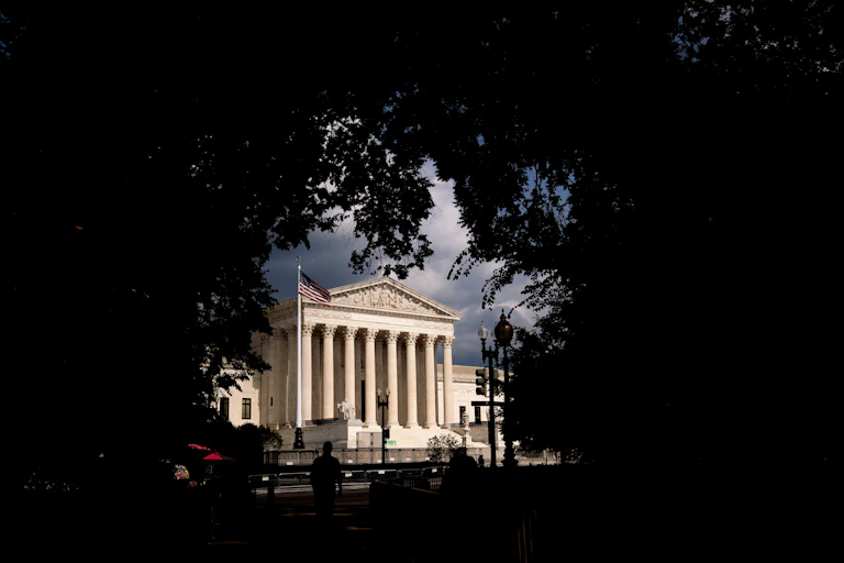The Supreme Court building is framed by trees.