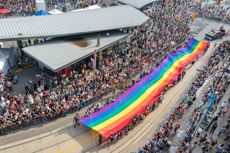 A massive pride flag is carried down the street