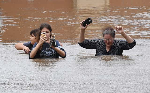 Family walks through deep flood waters