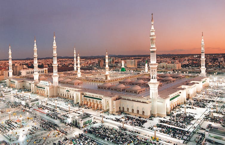 An overview of a large mosque compound at maghrib prayer time.
