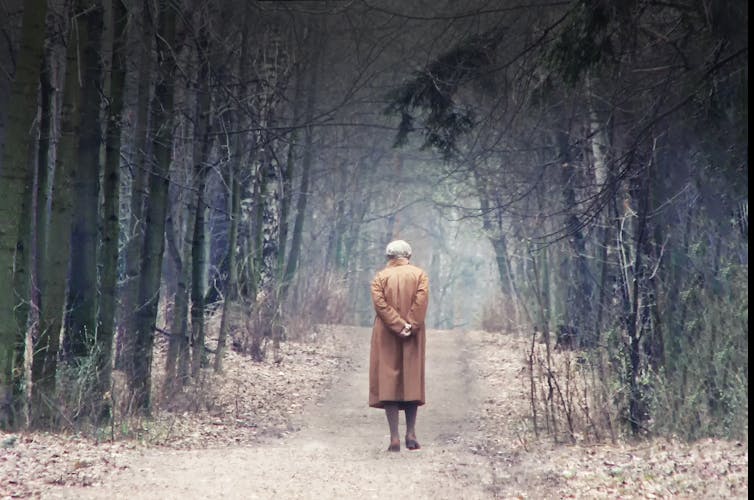 Old lady walking alone in the woods.