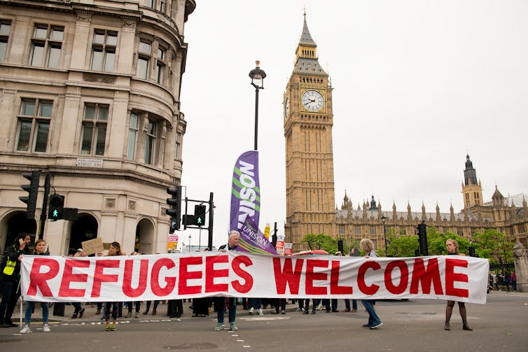 Protestors hold up a banner in a street.