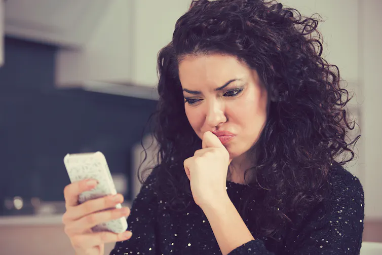 A woman looks confusedly at her mobile phone
