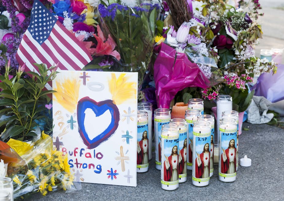 Flowers and candles at a memorial to the Buffalo shooting victims, a card apparently painted by a child reads Buffalo Strong and depicts a heart with angel wings