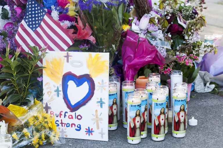 Flowers and candles at a memorial to the Buffalo shooting victims, a card apparently painted by a child reads Buffalo Strong and depicts a heart with angel wings