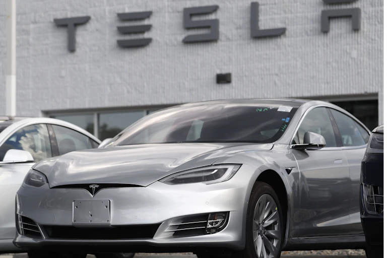 a sleek silver car under a TESLA sign
