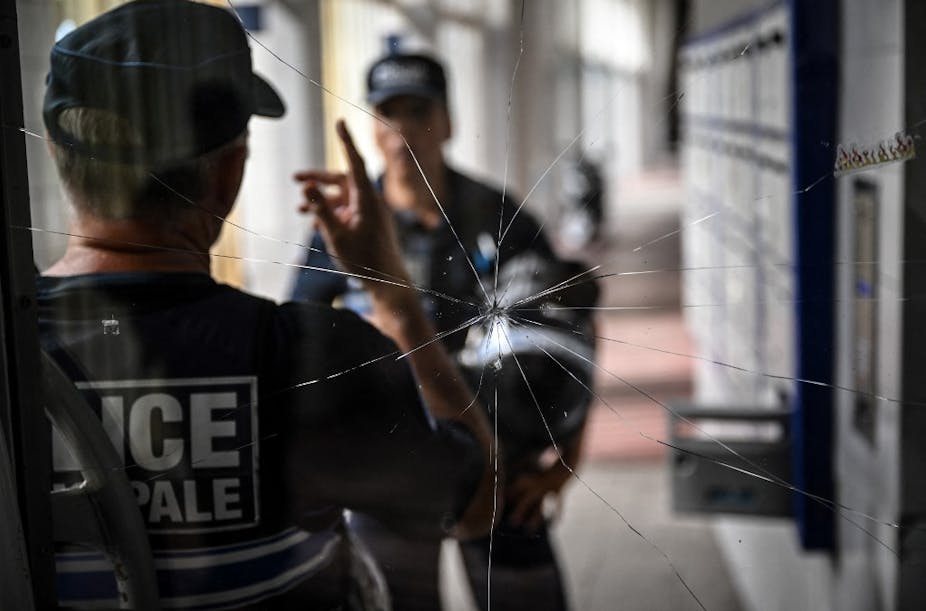 Deux policiers discutent devant une vitre brisée à Lyon La Duchère le 15 juin 2022