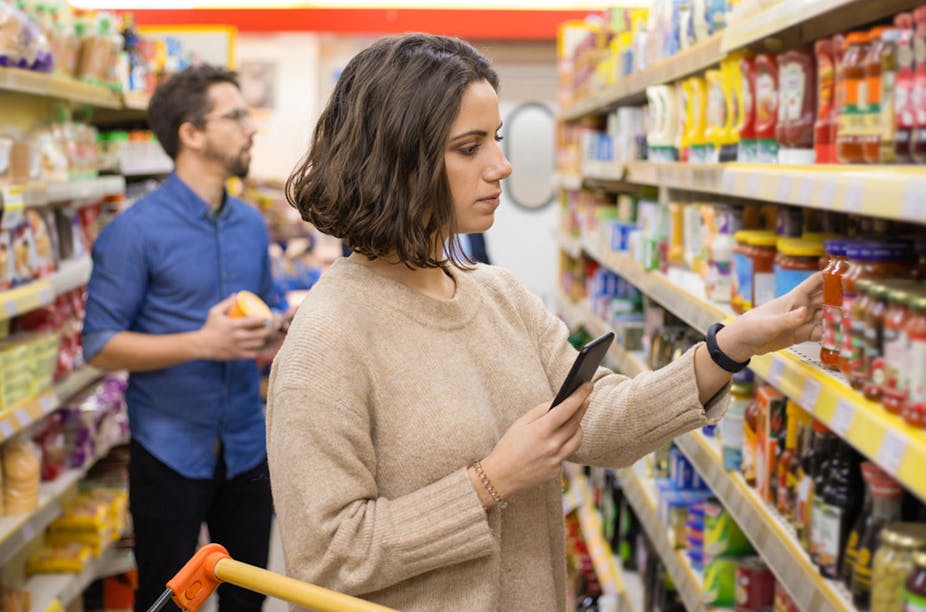 A woman in a supermarket looks at products on the shelf.
