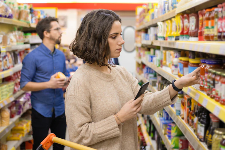 A woman in a supermarket looks at products on the shelf.