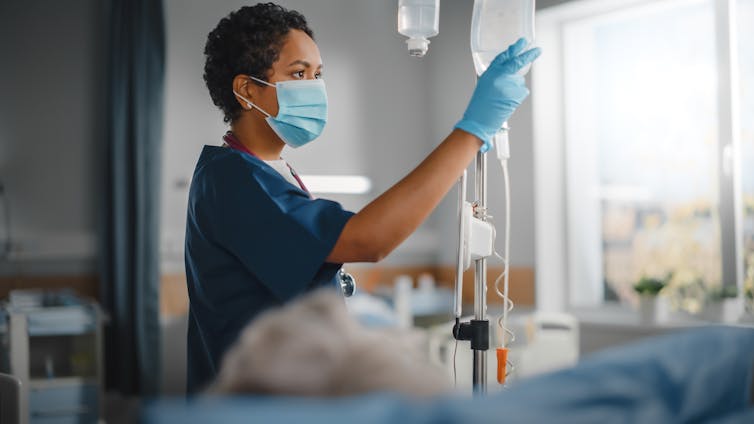 Nurse checking infusion bag hanging on IV pole