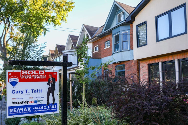 A real estate sign on the lawn of a house