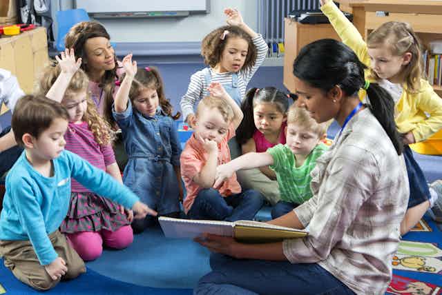 Teacher holding a book asks preschoolers a question