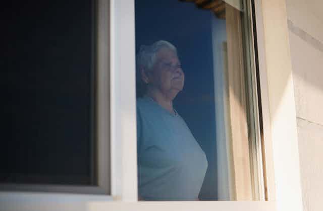 older woman looks out the window
