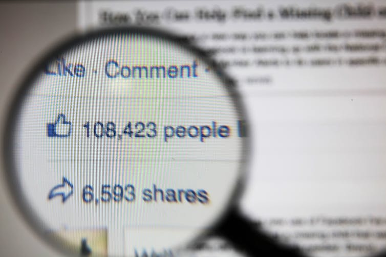 A magnifying glass hovers over a Facebook post's likes