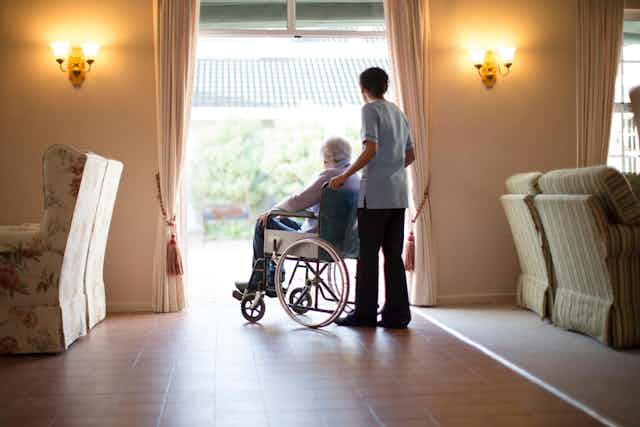 A nurse pushes an elderly patient in a wheelchair.