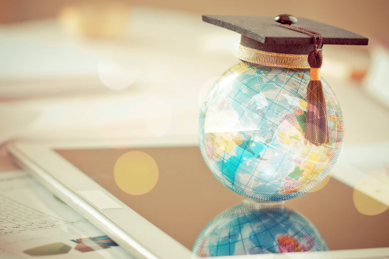 A graduation hat on top a Earth globe model map.