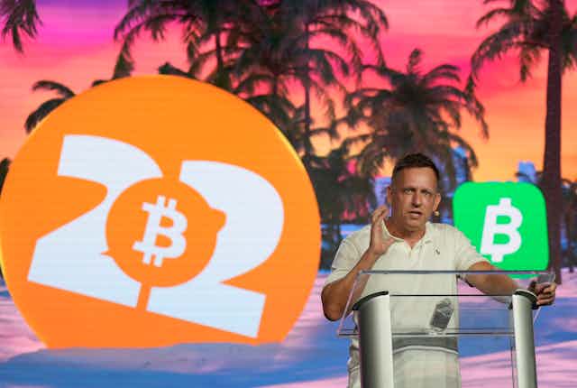 homme devant un écran avec le symbole de Bitcoin