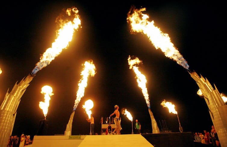 Several fireballs shoot into the air as a man performs.