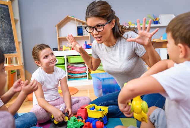Early childhood teacher gestures as she talks with young children