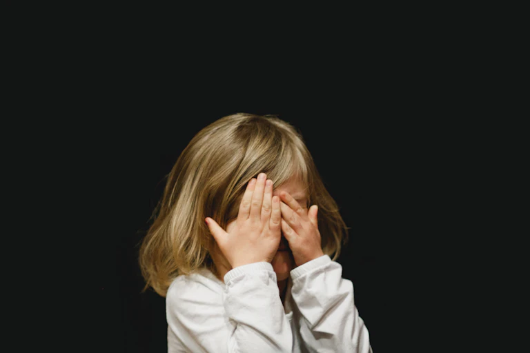 little girl covers face with hands