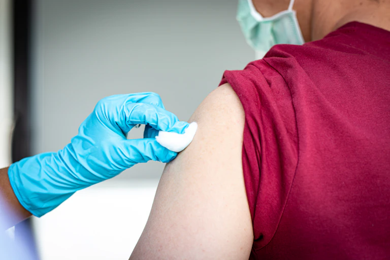 Nurse holds a cotton bud to patient's arm after vaccination.