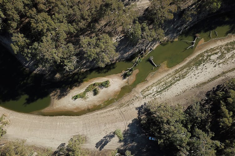 An aerial photo of a river with little water in it. Dried-out banks are visible