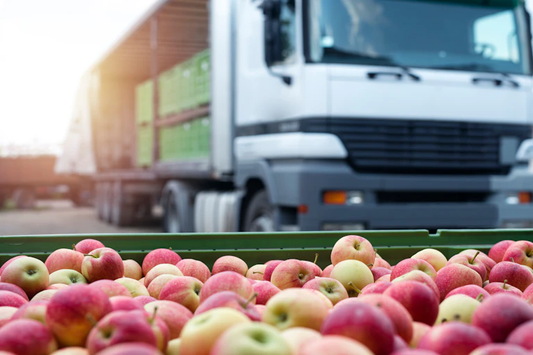pile of apples with truck in background