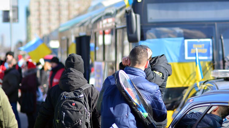A queue of people getting on a train with Ukrainian flags.