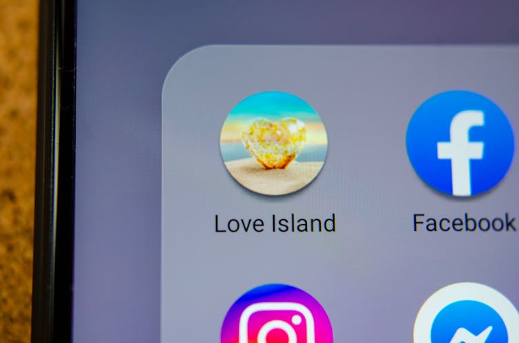 A close up image of the Love Island app icon alongside other apps on a smartphone
