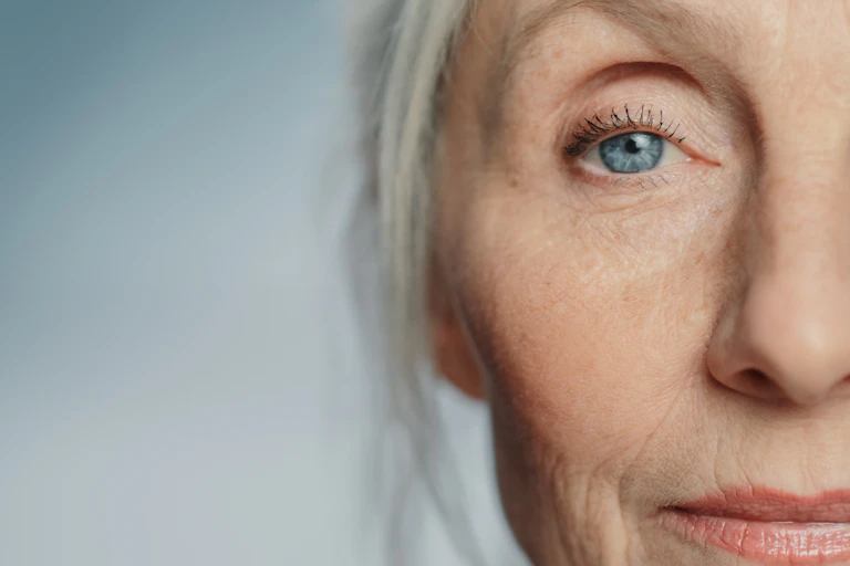 Close up of one half of a white-haired woman's face with striking blue eyes