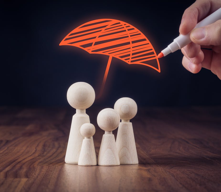 Dolls representing a family having an umbrella drawn over them to represent insurance