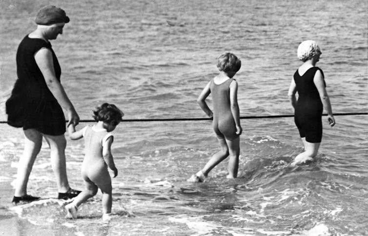 Une famille entre dans l’eau en maillot de bain une pièce en 1937