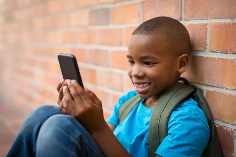 Boy with rucksack on looking at mobile phone
