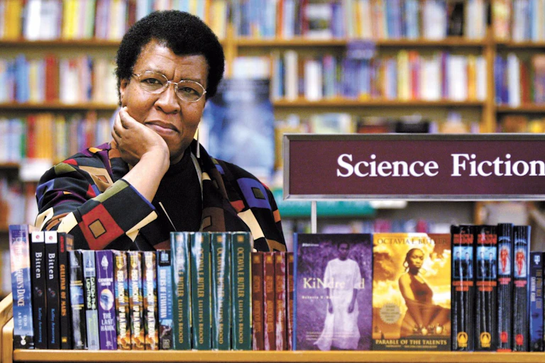 Woman rests head in hand posing over bookshelf.