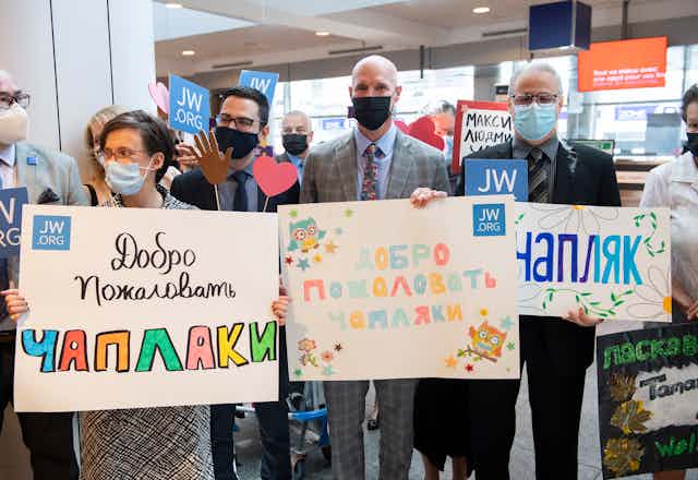 People hold signs at the airport welcoming Ukrainians