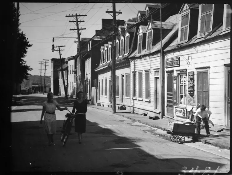 Women walk down the street holding a bike