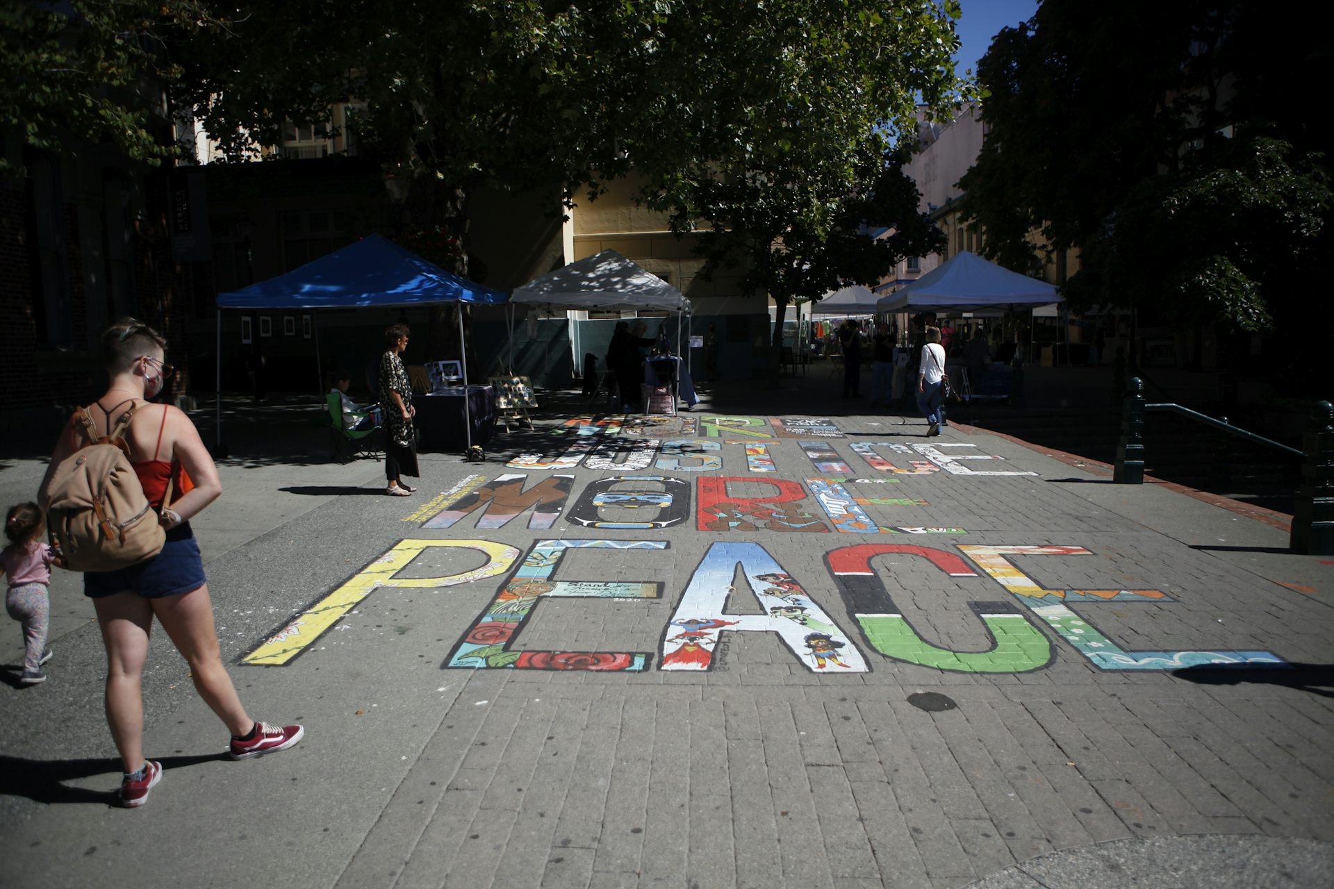 People look at a mural painted on the ground that reads More Justice More Peace.