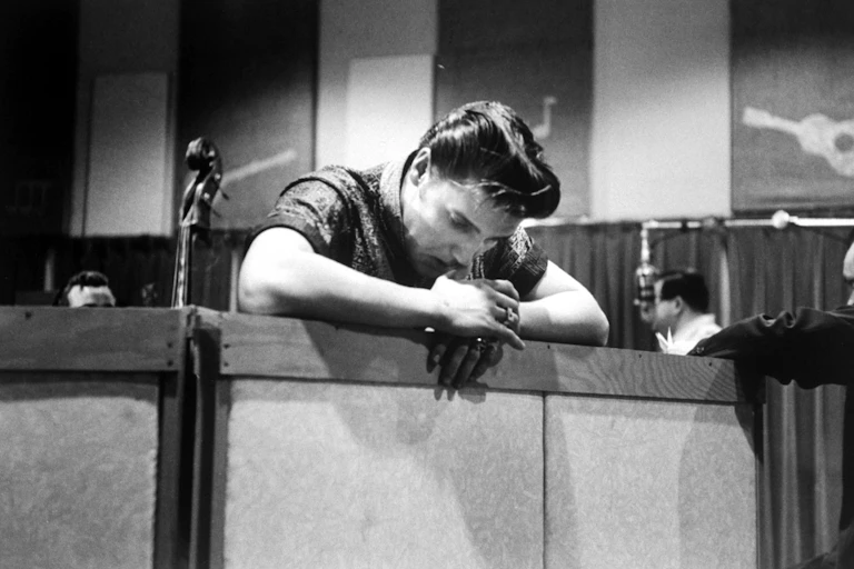 Man leans over railing deep in thought.