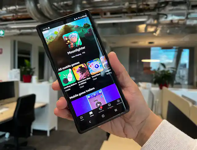 A phone with Netflix's game screen is held up in an office